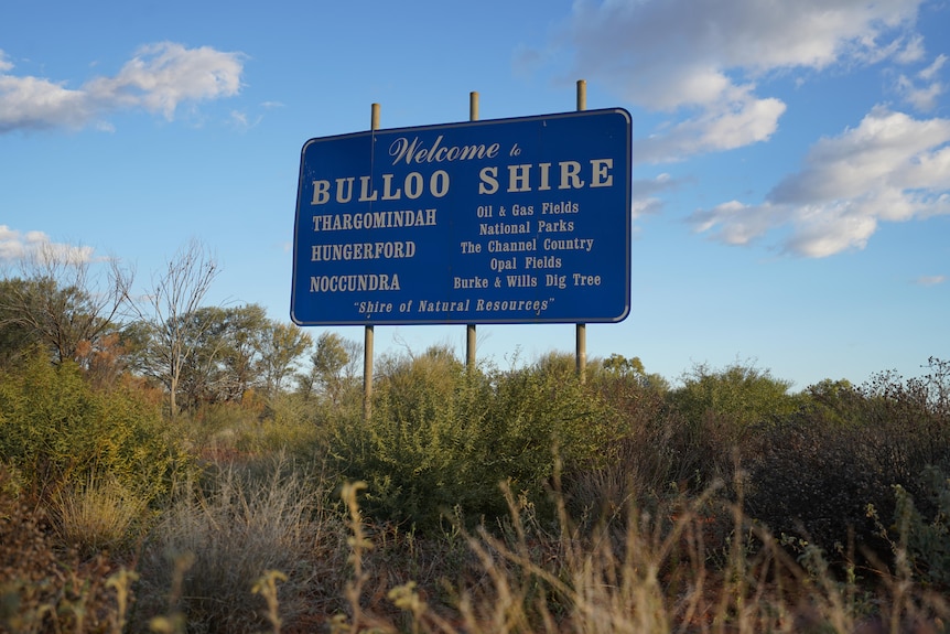 Blue sign saying Bulloo Shire next to green bushes