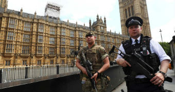 A soldier and police officer walk past UK's Houses of Parliament.