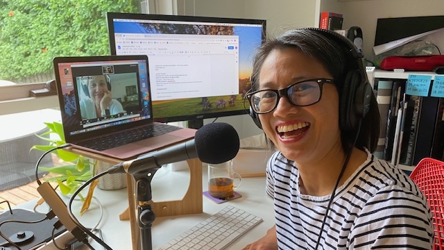 Lisa smiles into the camera as she records in her home office with producer Maria Tickle on the screen in the background