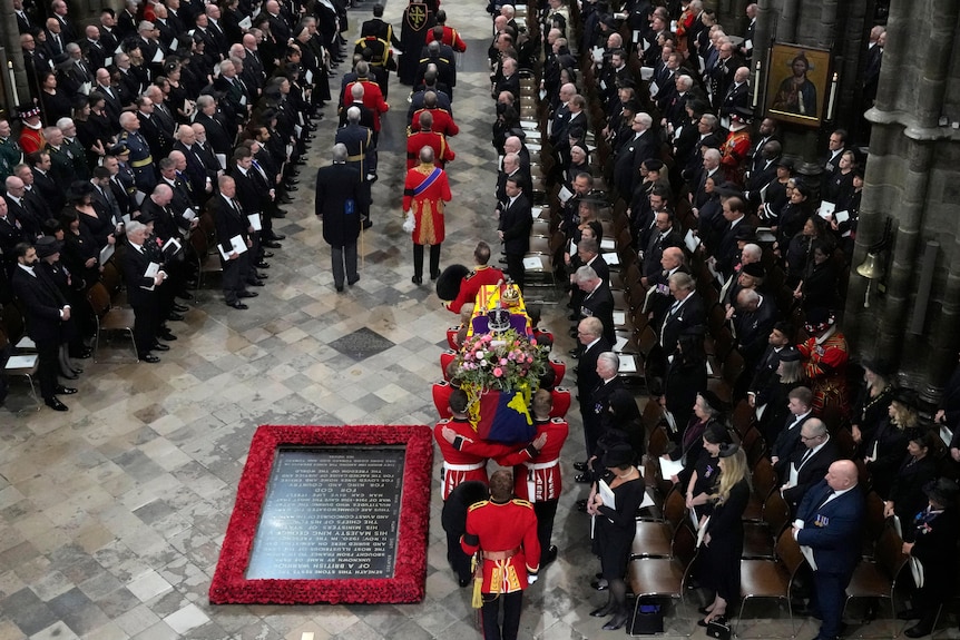 Military officials hold the Queen's coffin as they carry it into Westminster Abbey 