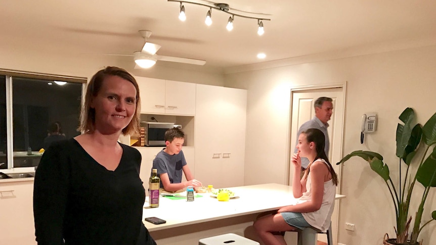 Kate Neale in her kitchen with family in the background