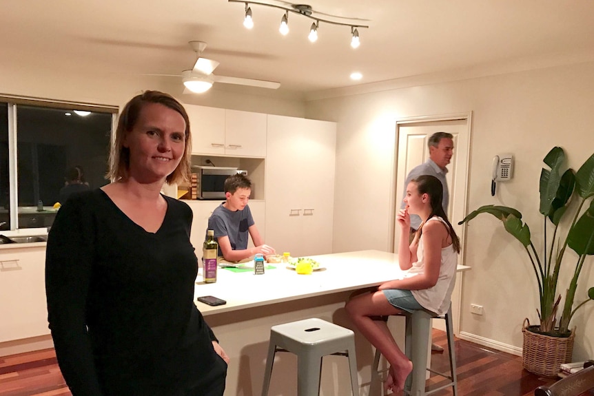 Kate Neale in her kitchen with family in the background