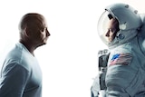 A man in a white shirt facing a man in an American space suit.