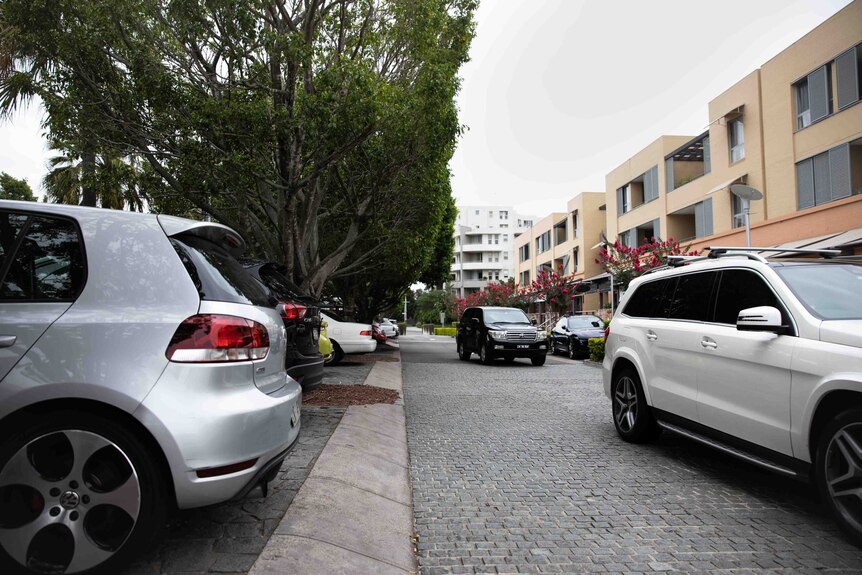 Cars parked as other cars queue on road