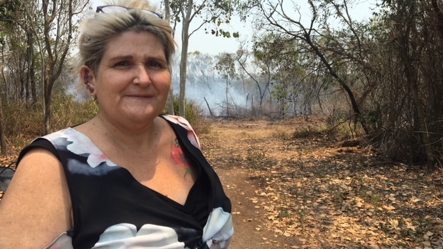 Sarina beach resident Vicky Crichton standing on her property with smoke in the background.