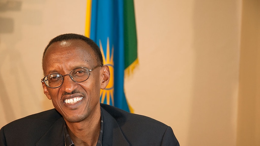 Rwandan President Paul Kagame smiles, pictured in his office in front of the Rwandan national flag