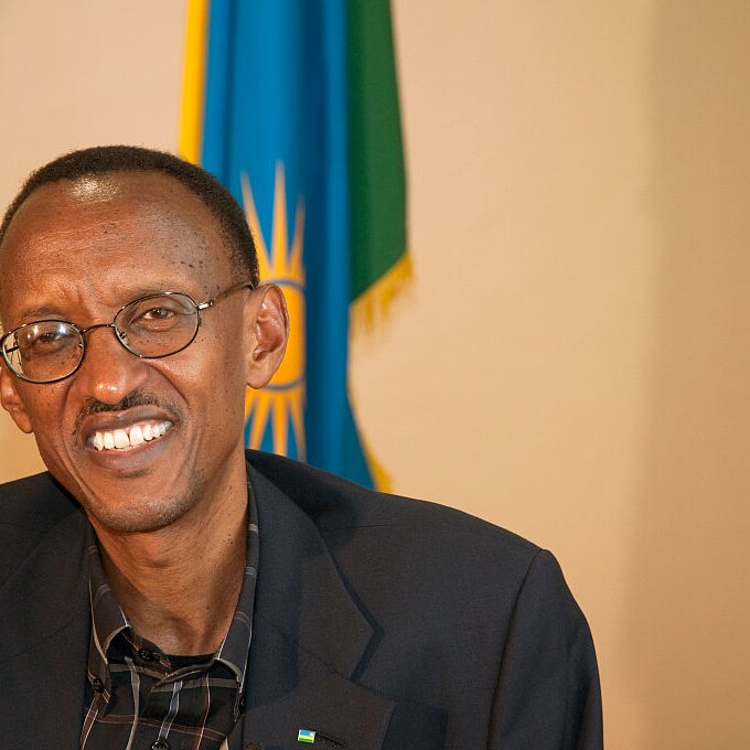 Rwandan President Paul Kagame smiles, pictured in his office in front of the Rwandan national flag
