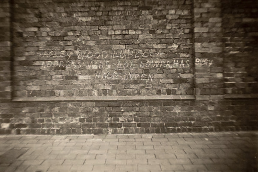 A brick wall covered in white chalk with Bella written on it.