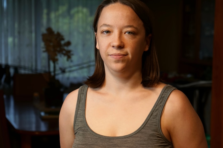 Woman wearing tank top in a dark room.