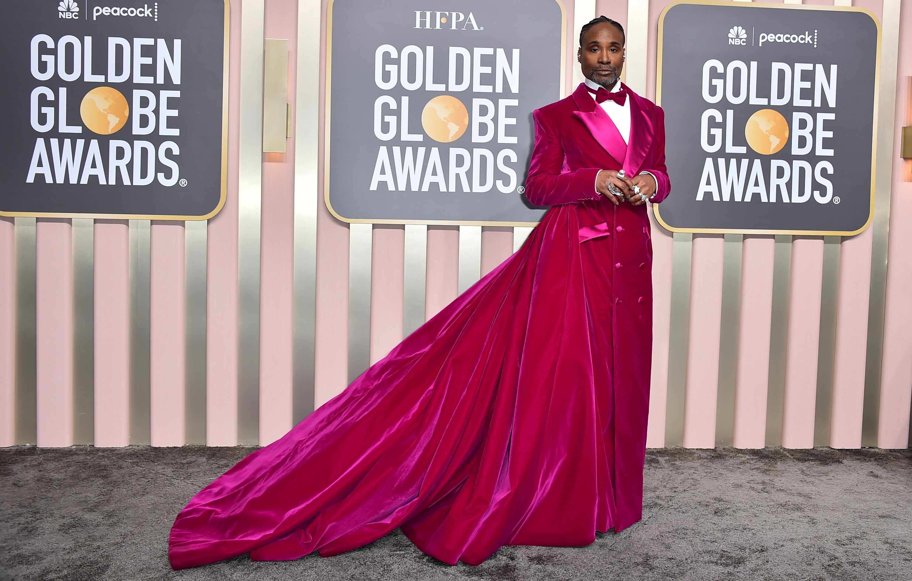 Billy Porter wearing a bright pink tuxedo gown with a long train