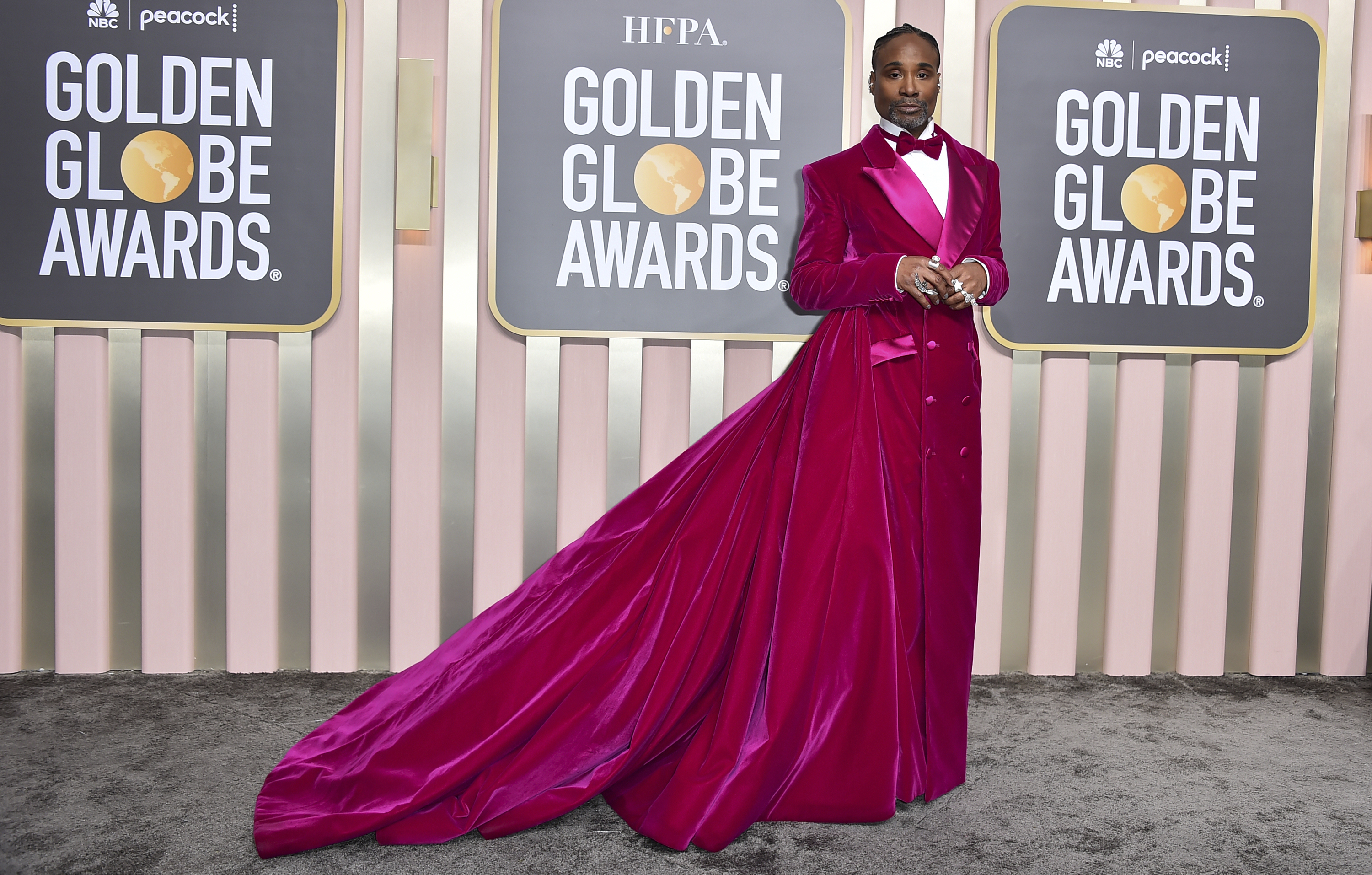 Billy Porter wearing a bright pink tuxedo gown with a long train