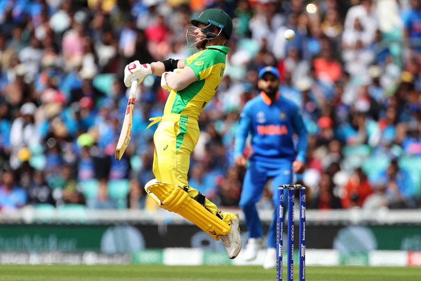 David Warner jumps and plays the bat away from his body as the ball flies past his head