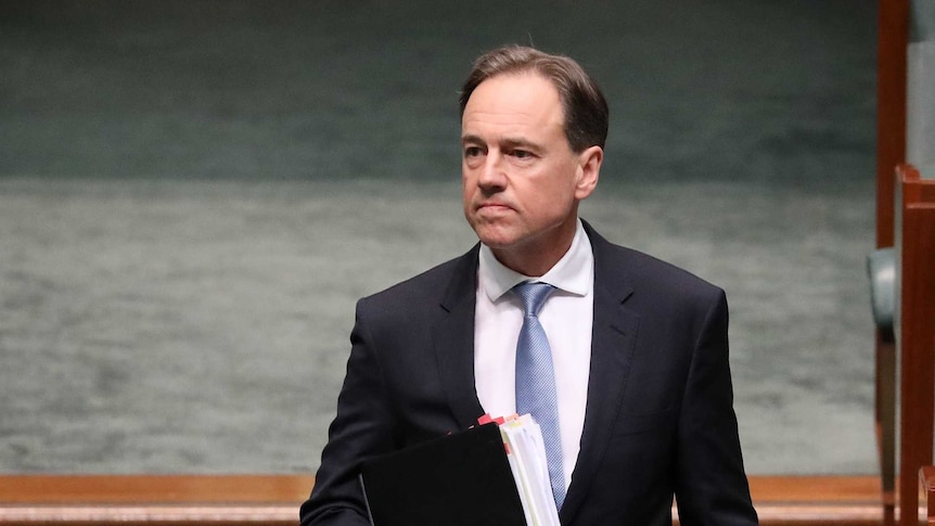 Greg Hunt walks into the House of Representatives and looks towards the Opposition's benches