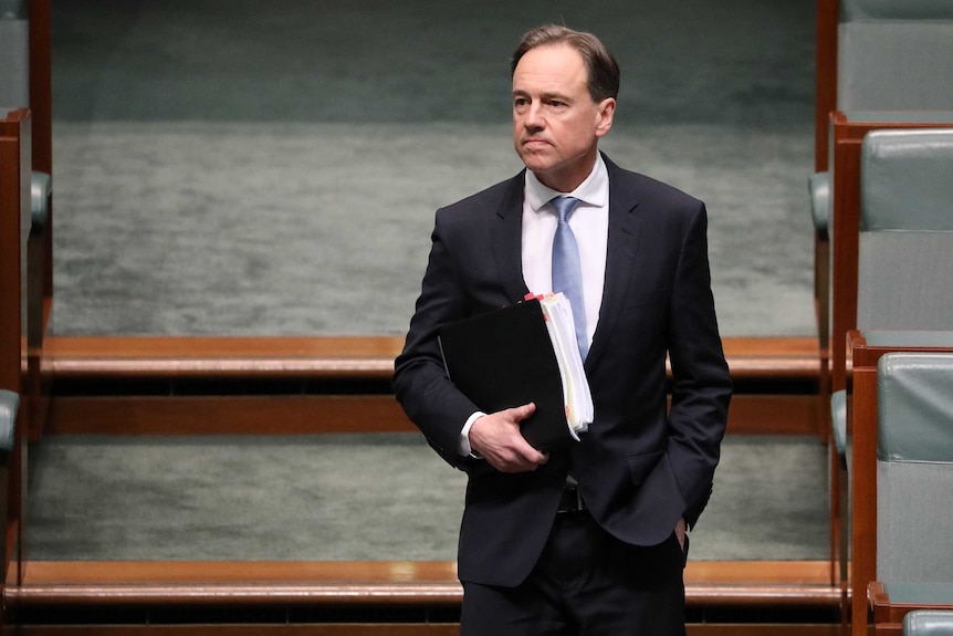 Greg Hunt walks into the House of Representatives and looks towards the Opposition's benches