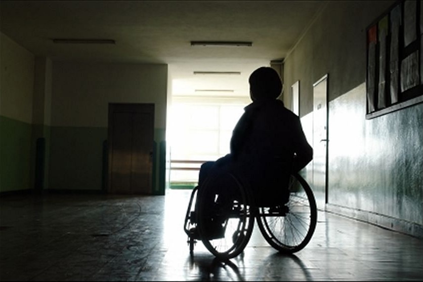 A generic image of a person sitting in a wheelchair in a dark room.