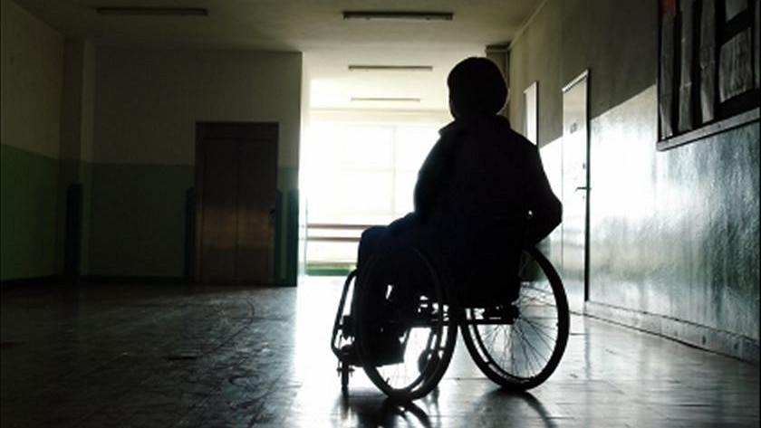 A generic image of a person sitting in a wheelchair in a dark room.