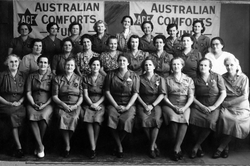 women pose in front of a banner