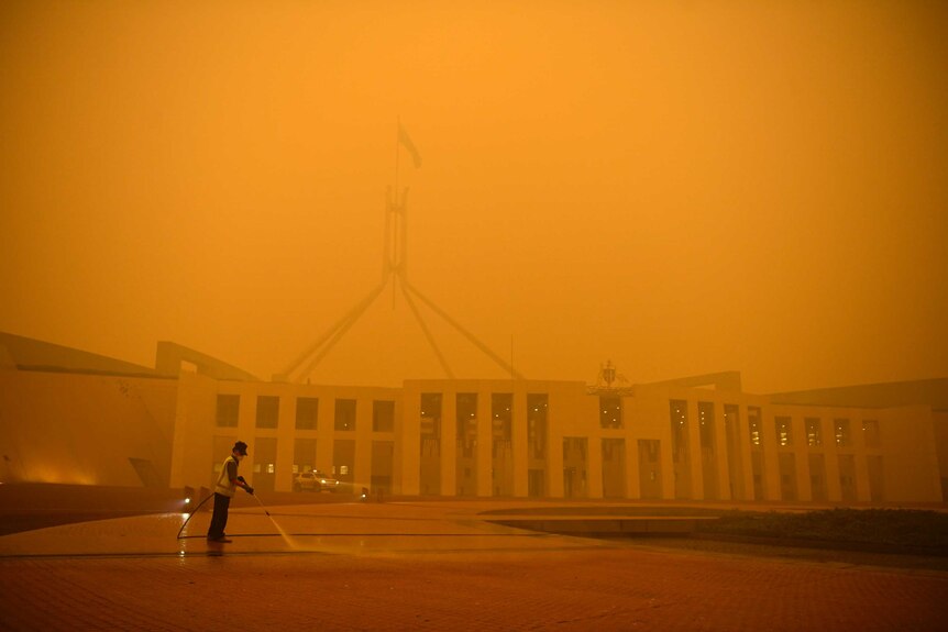 Orange haze of bushfire smoke obscures Parliament House.