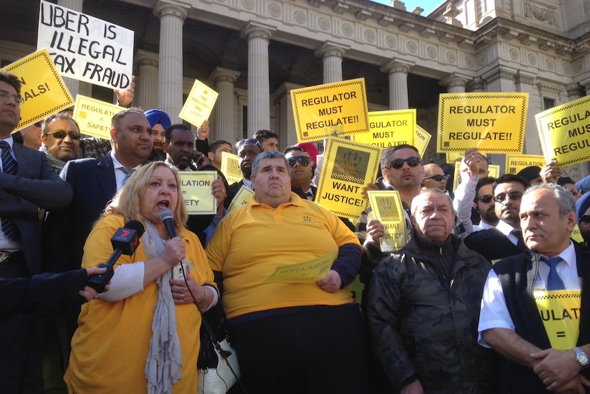 Taxi drivers rally against Uber on the steps of Victoria's Parliament House.