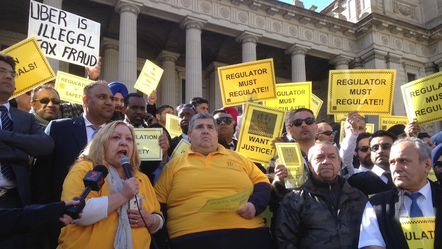 Taxi drivers rally against Uber on the steps of Victoria's Parliament House.