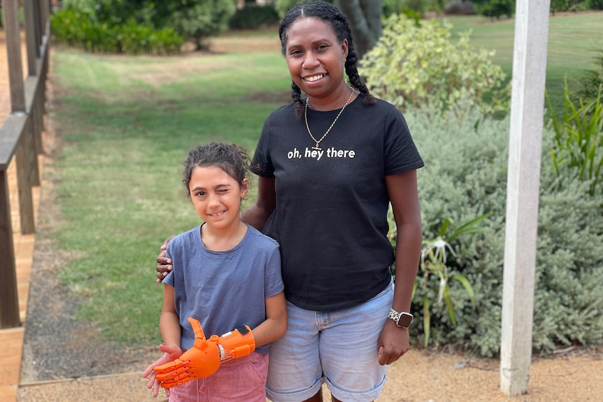 A mother and daughter stand outside smiling