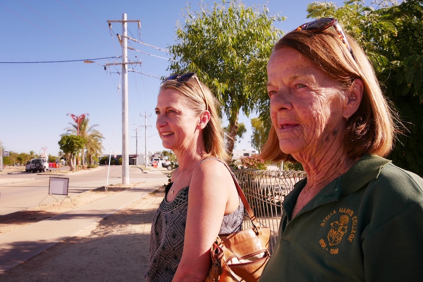 Two women standing at the side of a road.