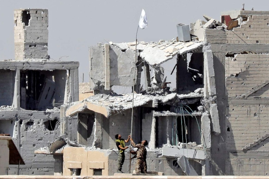 Fighters of Syrian Democratic Forces raise a white flag near the National Hospital complex.