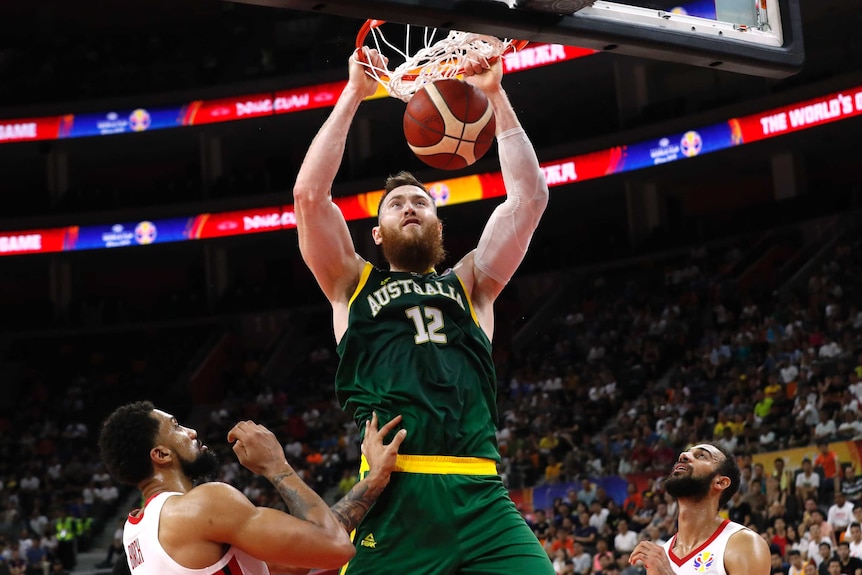 The ball is just through the hoop as Aron Baynes completes the dunk. Two Canadian players look on.