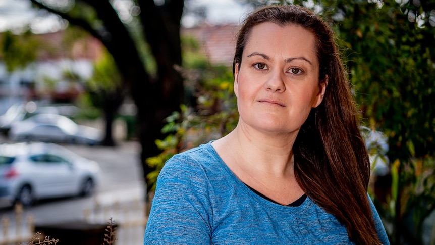 A woman in a garden staring into the camera.