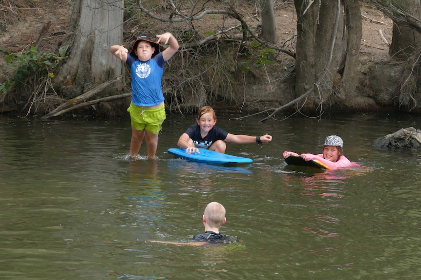 Four children swimming in the river at Cotter reserve.