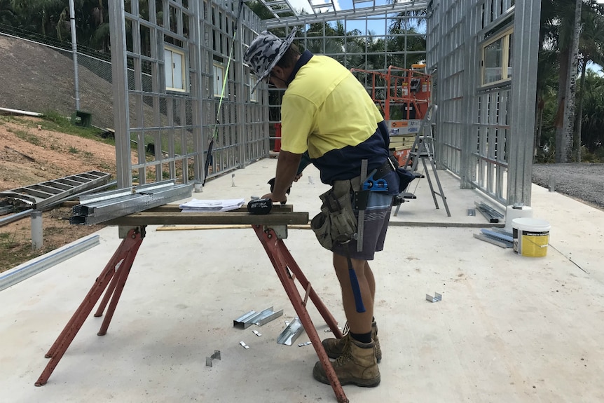 A worker cutting metal standing in front of an uncompleted steel structure.