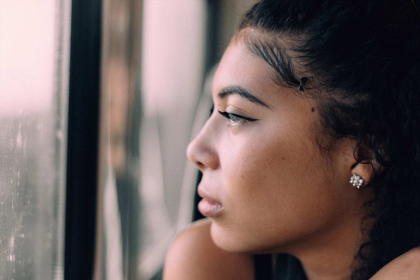 Upset woman looking out the window to depict what to do when you're fired on maternity leave.