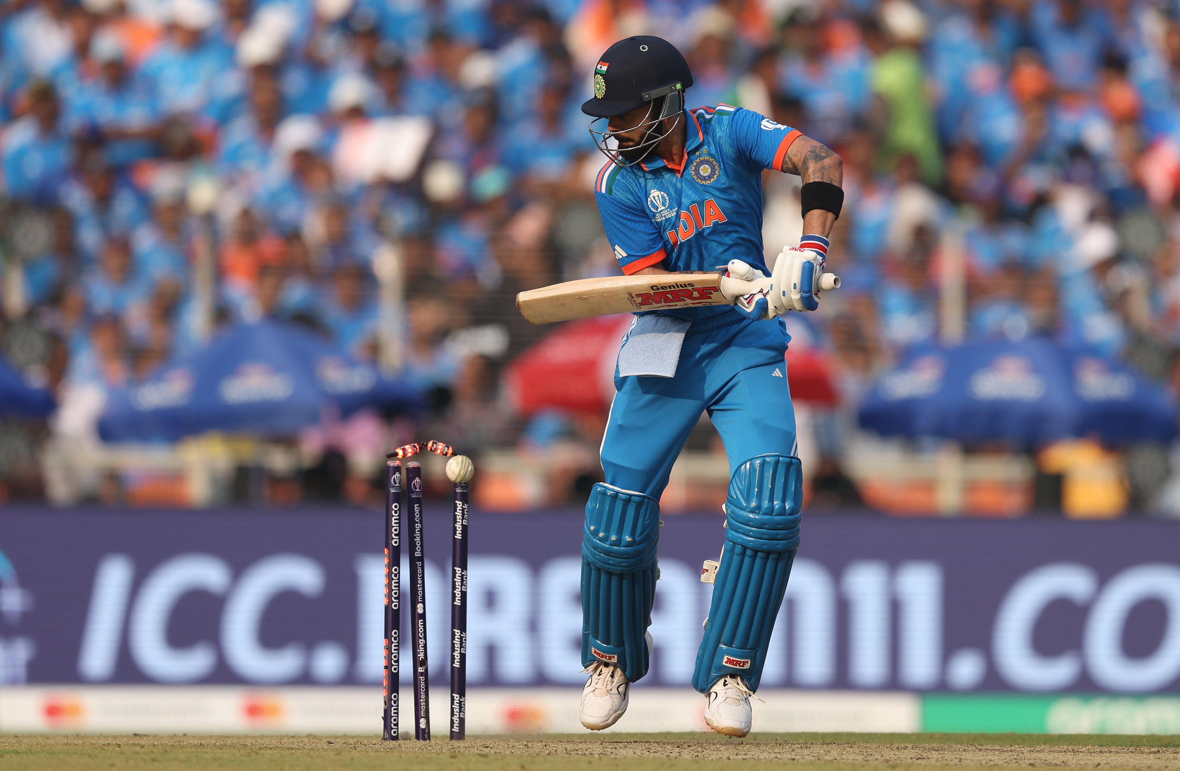 An Indian batter, playing off the back foot, hits the ball onto his stumps