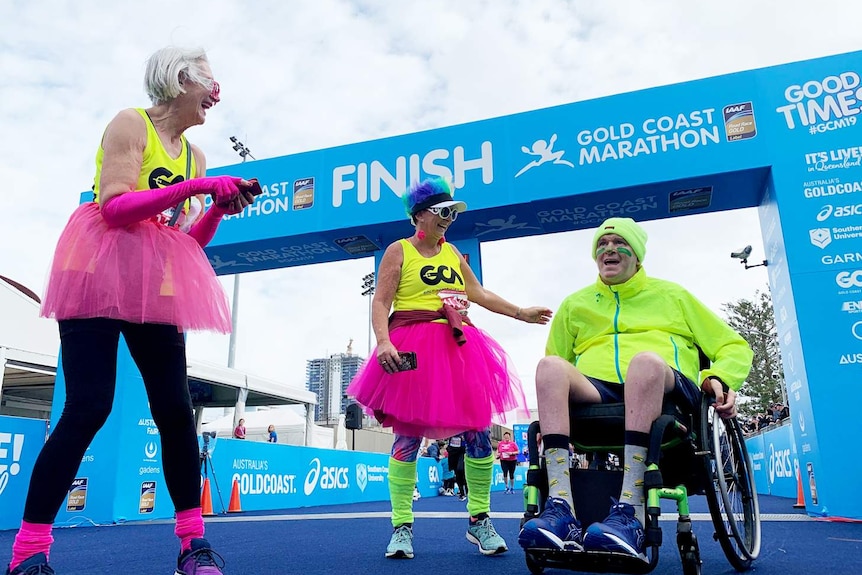 Two women stand beside Brett Morris at the race finish line.