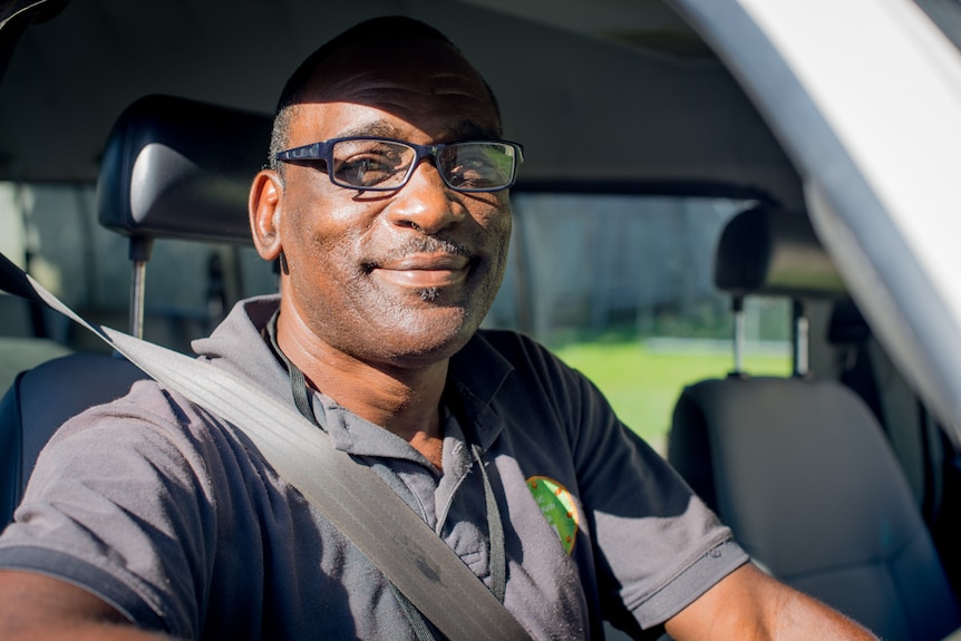 A man sits in the drivers' seat of a community school bus, ready to take underprivileged children to school.