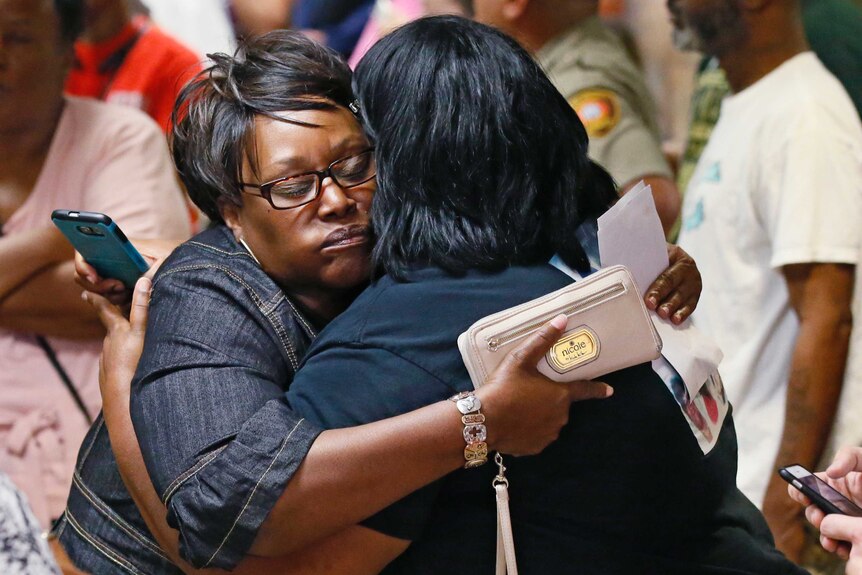Two women embrace after leaving the courtroom.