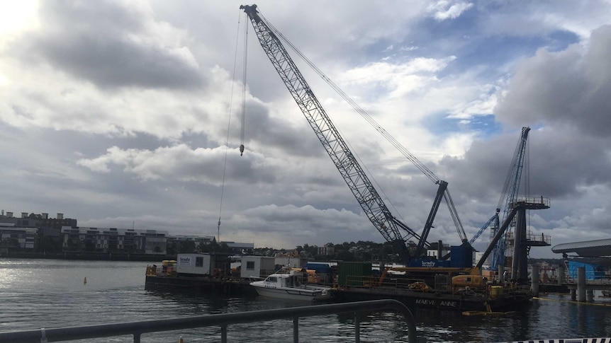 A barge with a crane hovering over the top and police boat.