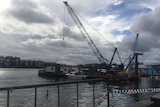 A barge with a crane hovering over the top and police boat.