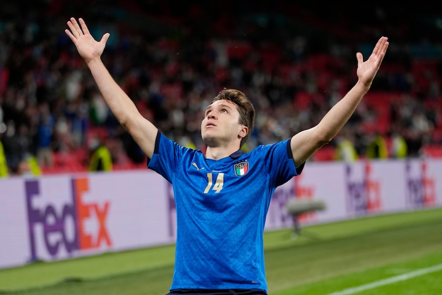 An Italian soccer player raises his arms to the heavens in triumph after scoring a goal at Euro 2020.