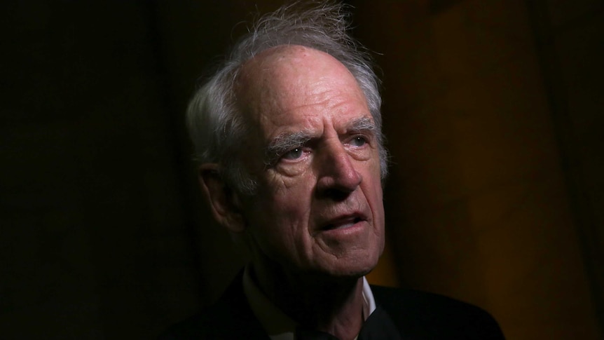 side portrait of philosopher charles taylor against pitch black background