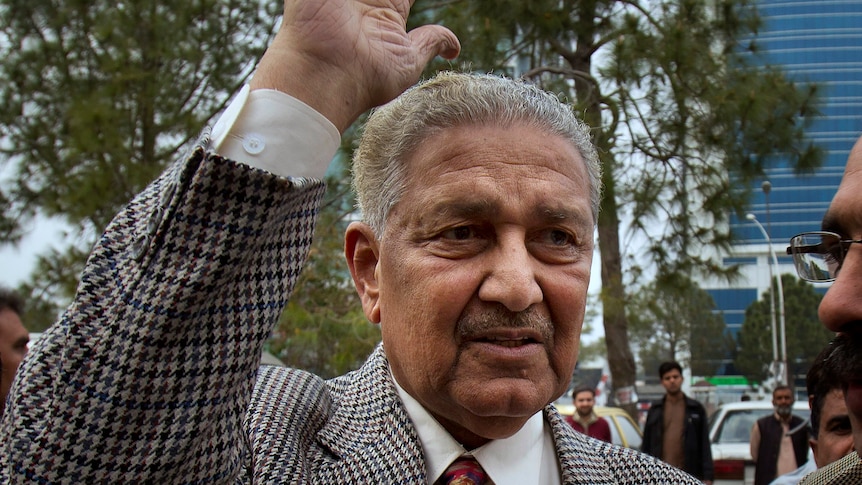 A man in a suit waves his hand 