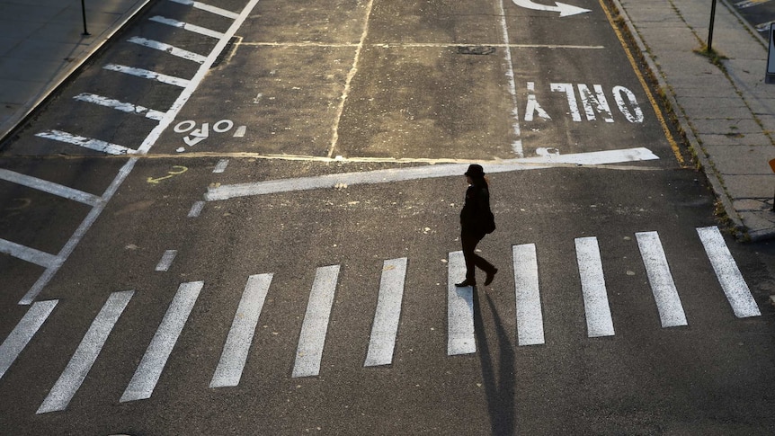 Lone woman crossing a completely empty street in Brooklyn, New York.