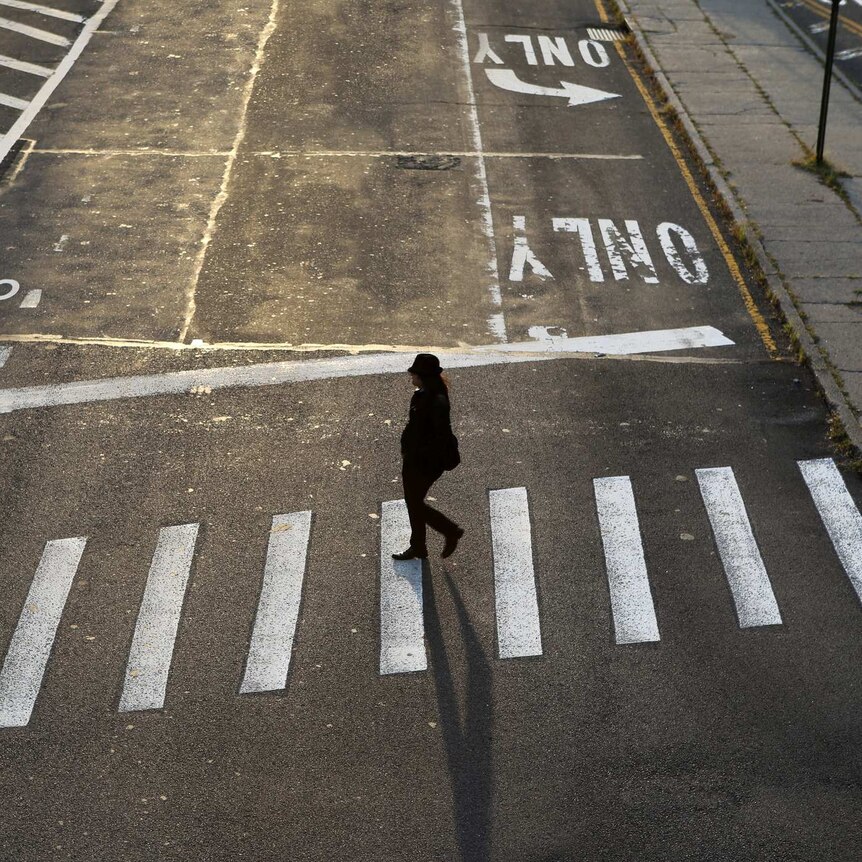 Lone woman crossing a completely empty street in Brooklyn, New York.