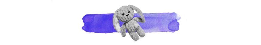 knitted soft toy in black and white on top of a wash of purple colour