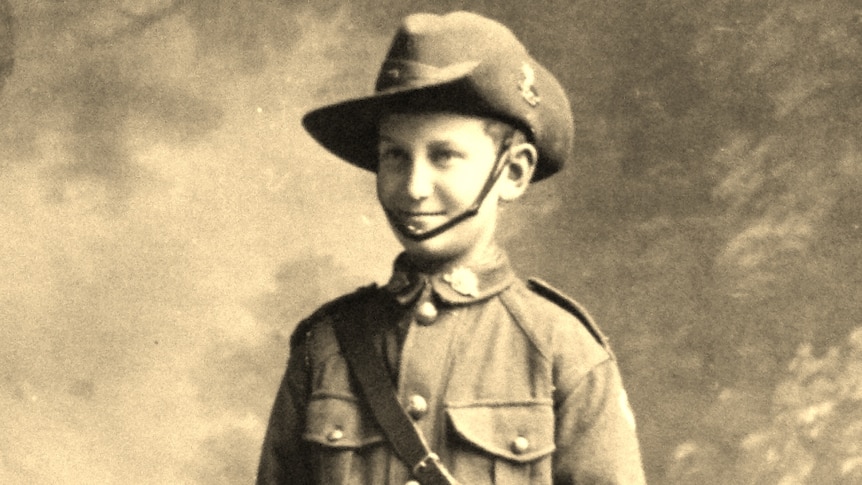 A young boy stands dressed in Australian military uniform.