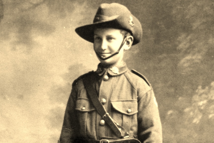 A young boy stands dressed in Australian military uniform.