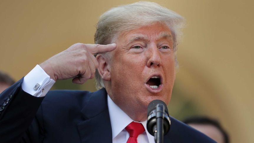 US President Donald Trump putting a finger to his head, while saying the journalists are 'loco' (crazy) in a microphone.
