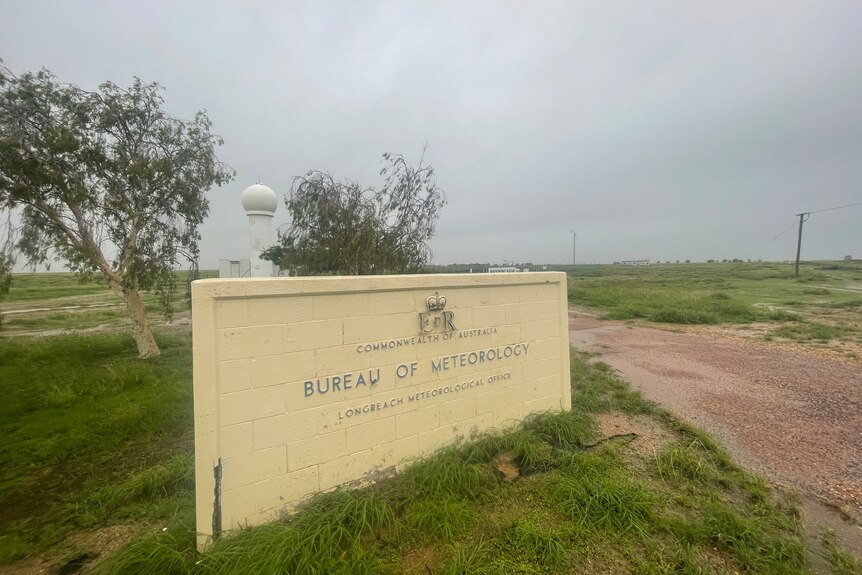 A sign for the BOM with clouds overhead.