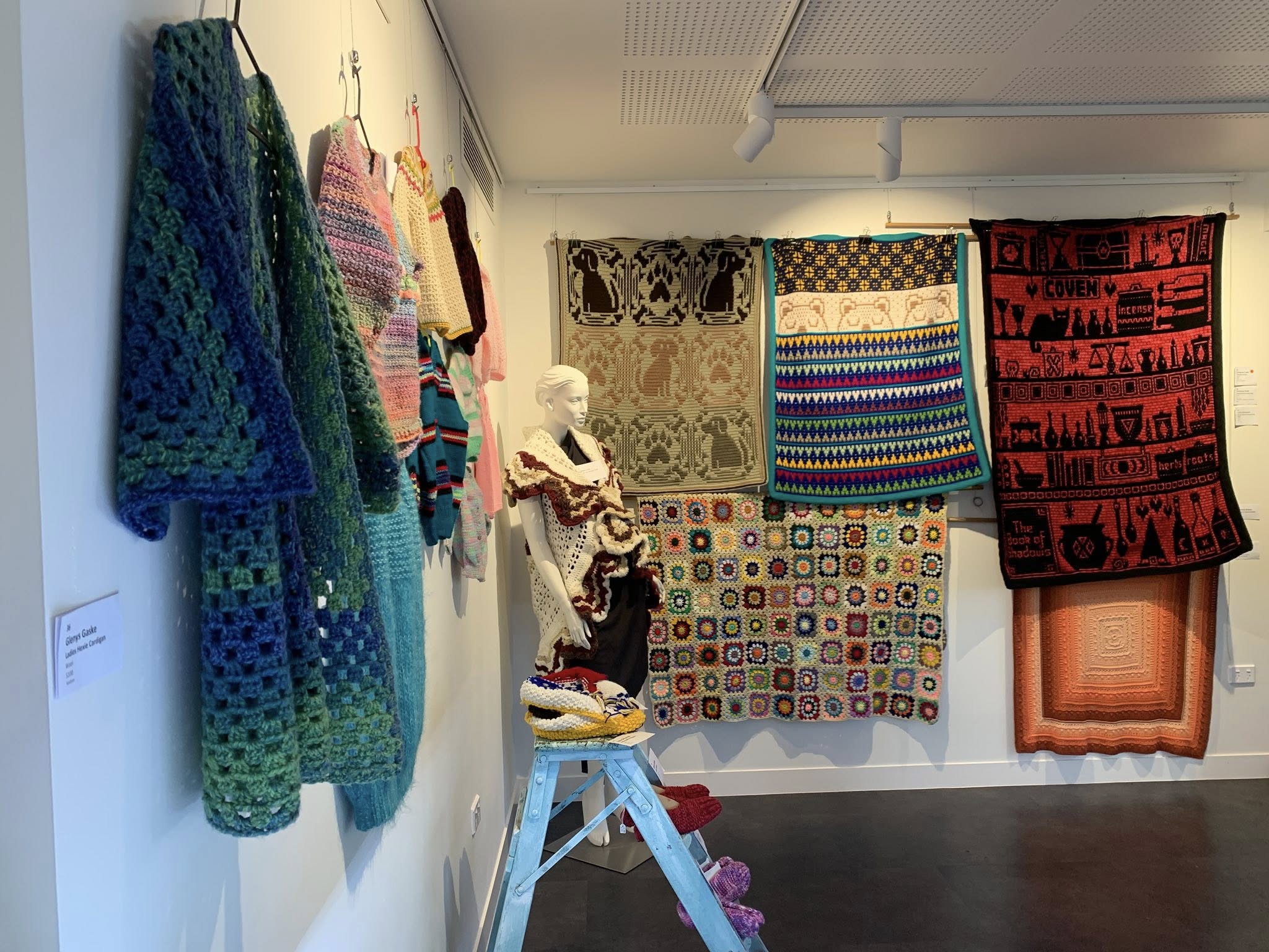 Uma parede de galeria coberta com bordados de artistas locais. 