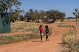 The back streets of Fitzroy Crossing with two girls walking along